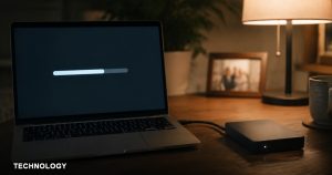 A laptop backing up files at night beside an external hard drive on a home desk.